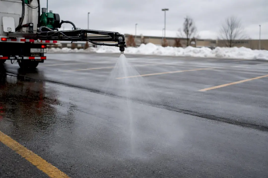 Brine sprayer applying anti-icing to parking lot