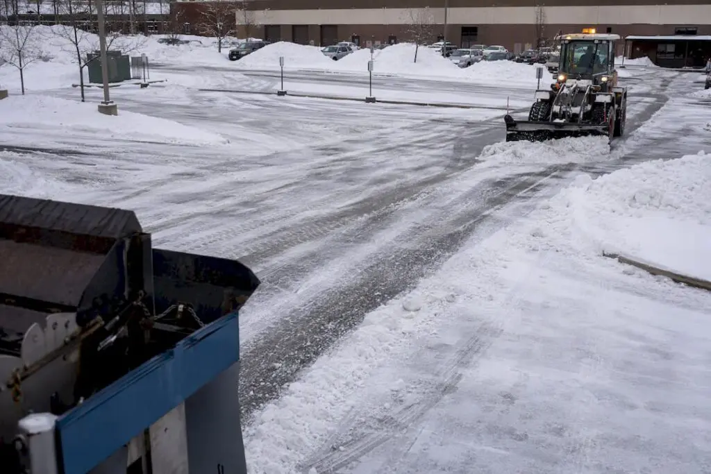 Snow plow clearing commercial parking lot