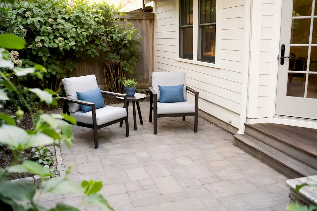 Small backyard patio with stone pavers and spaced furniture