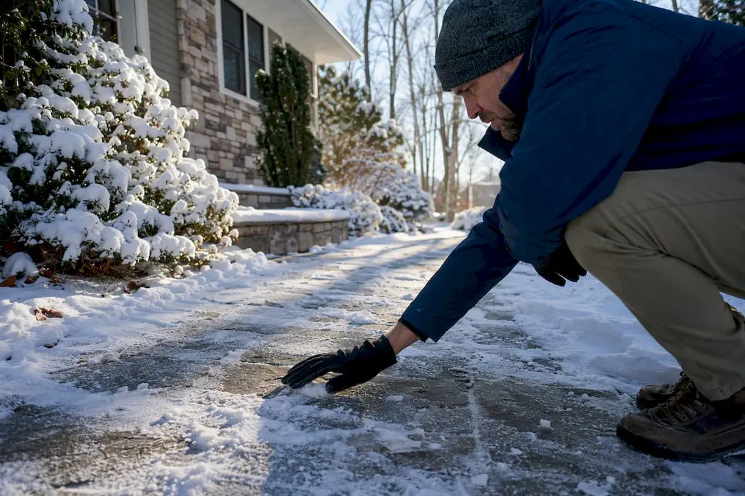 Hand inspecting frost on stone walkway
