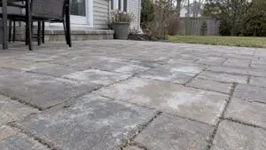 White mineral haze across concrete patio pavers